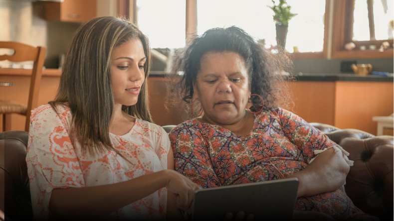 Two Aboriginal women look at some information on a laptop